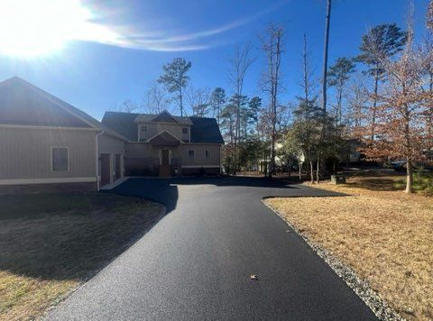 A driveway leading to a large house surrounded by trees on a sunny day.