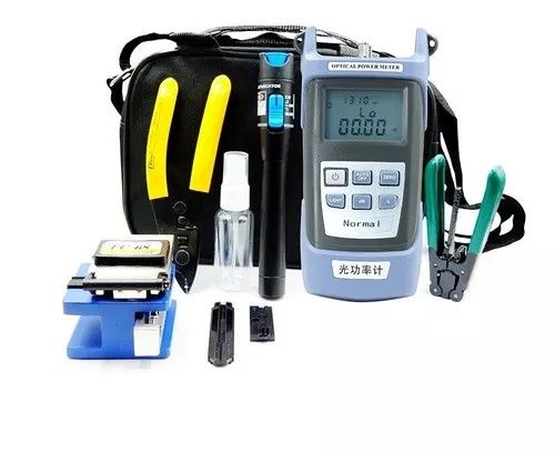 Un comprobador de fibra óptica está sobre una mesa al lado de una bolsa.