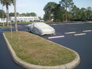 A car with a cover on it is parked in a parking lot.
