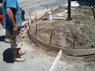 A group of construction workers are working on a concrete curb.