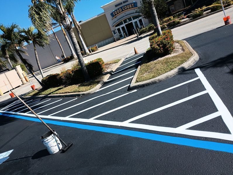 A parking lot is being painted blue and white with a broom.