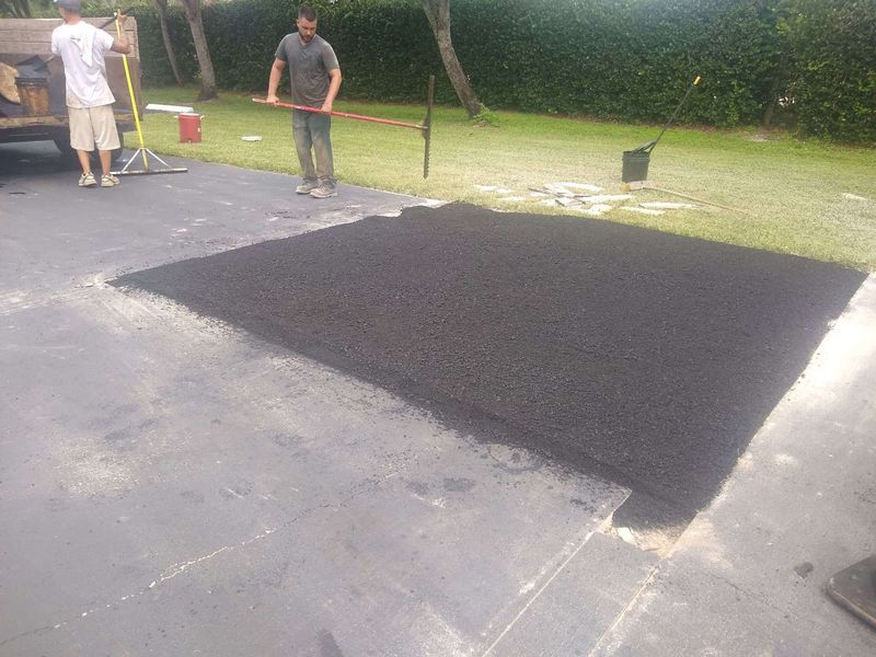 A man is standing next to a large piece of asphalt in a driveway.