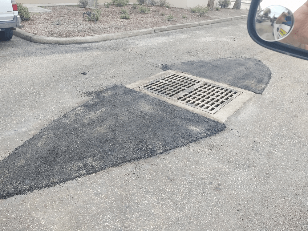 A person is looking at a manhole cover in their rear view mirror.