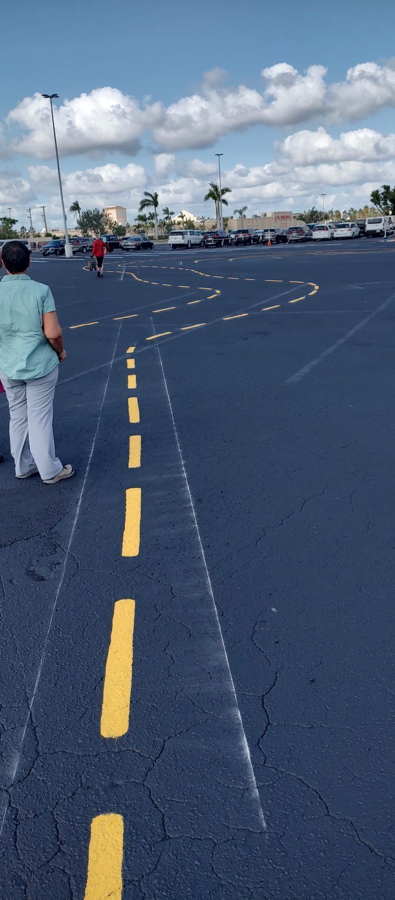 A woman is walking down a road with yellow lines on it.
