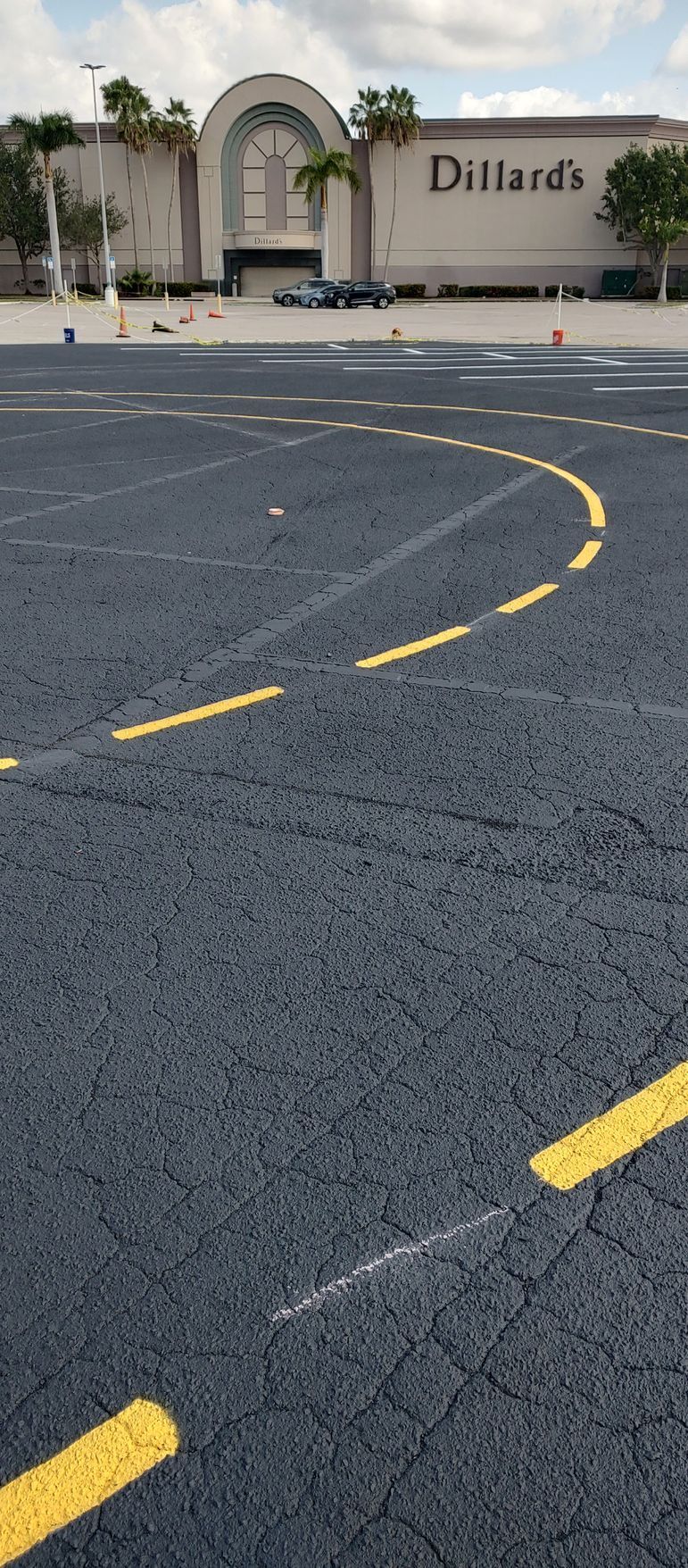 A parking lot with yellow lines and a building in the background.