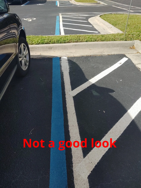 A black car is parked in a handicapped parking space