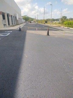 A road with a lot of cones on it and a building in the background.
