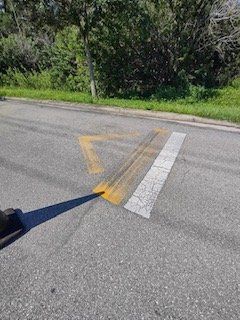A person is walking down a street with a yellow line painted on the side of the road.