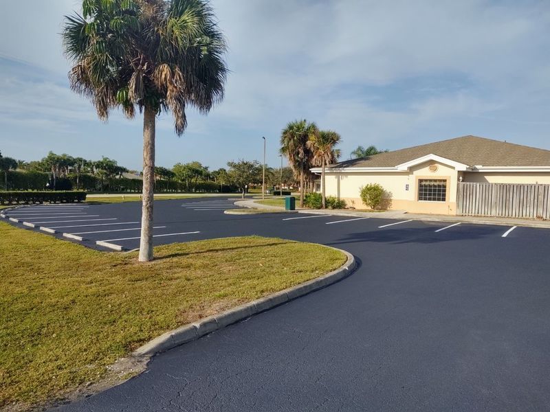 A parking lot with a palm tree and a house in the background