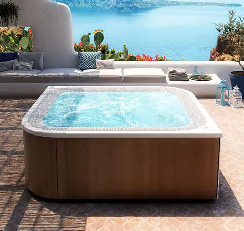 Un grand jacuzzi est installé sur une terrasse à côté d'un canapé.