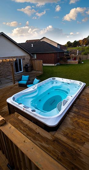 Un bain à remous est posé sur une terrasse en bois dans une cour arrière.