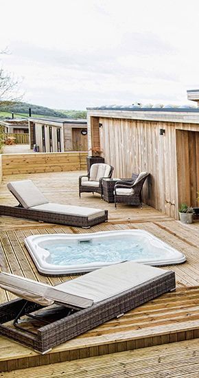 Une terrasse en bois avec un bain à remous et des chaises longues.