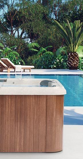 Un bain à remous en bois est installé à côté d'une piscine.