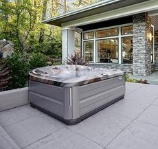 Un bain à remous est installé sur une terrasse devant une maison.