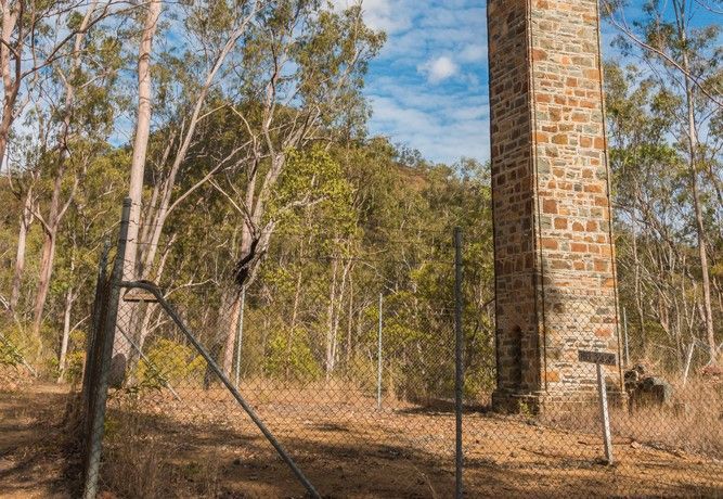 A Large Stone Tower Is Surrounded by Trees and A Fence — CK's Milling & Earthworks in Kilkivan, QLD