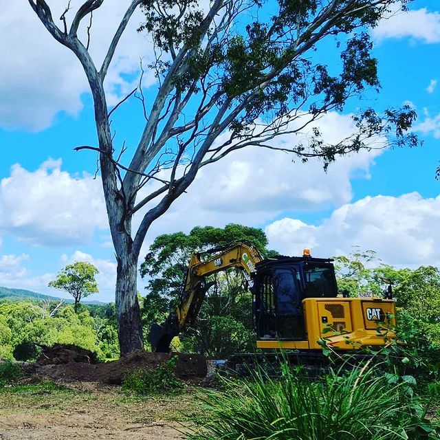 A Yellow Cat Excavator Is Digging a Hole in The Ground — CK's Milling & Earthworks in Bells Bridge, QLD