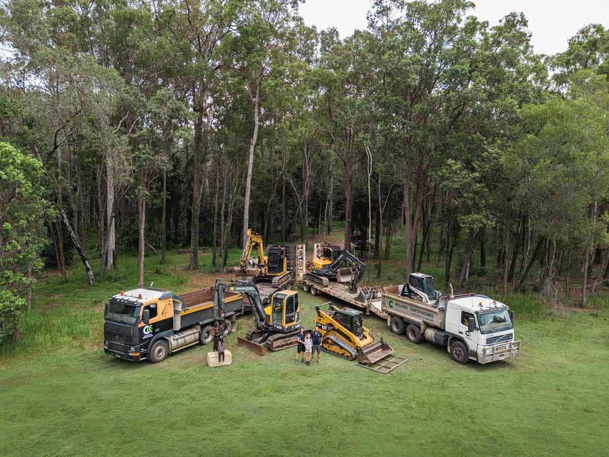 A Group of Construction Vehicles Are Parked in A Grassy Field — CK's Milling & Earthworks in Cooroy, QLD