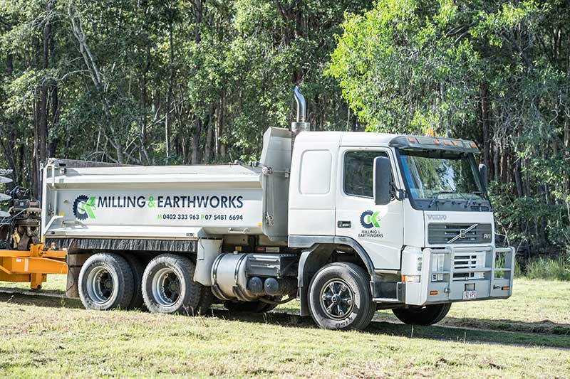 A Dump Truck Is Parked in A Field with Trees in The Background — CK's Milling & Earthworks in Bells Bridge, QLD