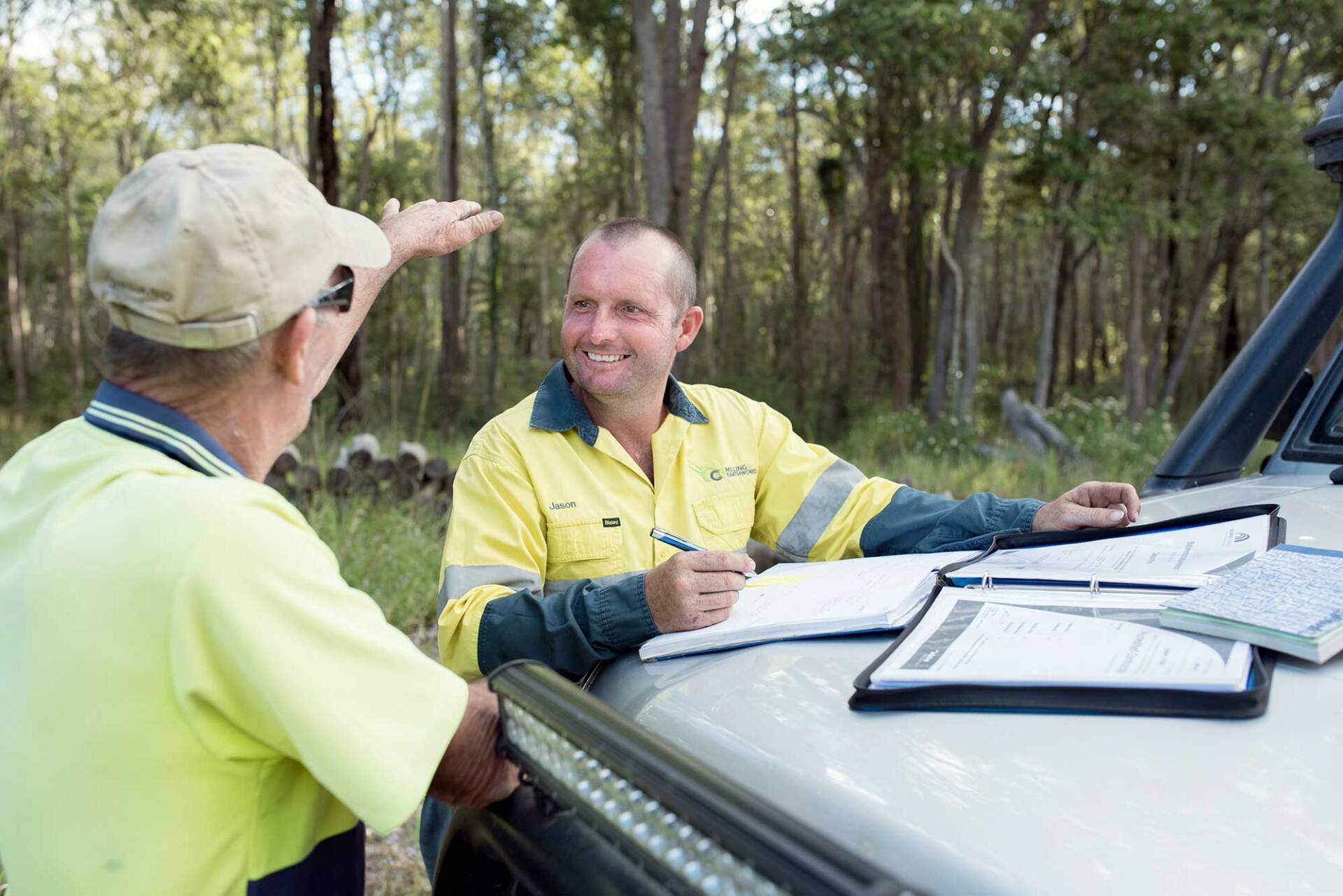 Two Men Are Sitting in The Back of A Truck Talking to Each Other — CK's Milling & Earthworks in Veteran, QLD