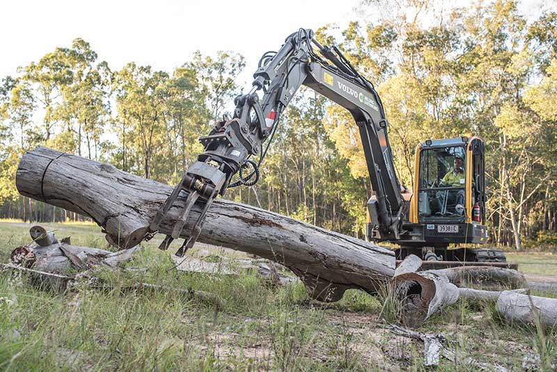 A Large Log Is Being Lifted by An Excavator in A Field — CK's Milling & Earthworks in Bells Bridge, QLD