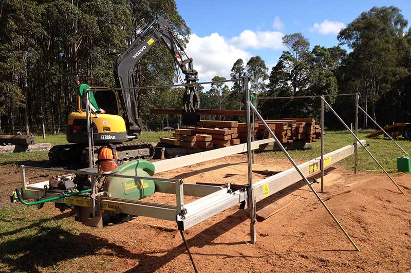 A Yellow Excavator Is Sitting on Top of A Trailer in A Field — CK's Milling & Earthworks in Bells Bridge, QLD