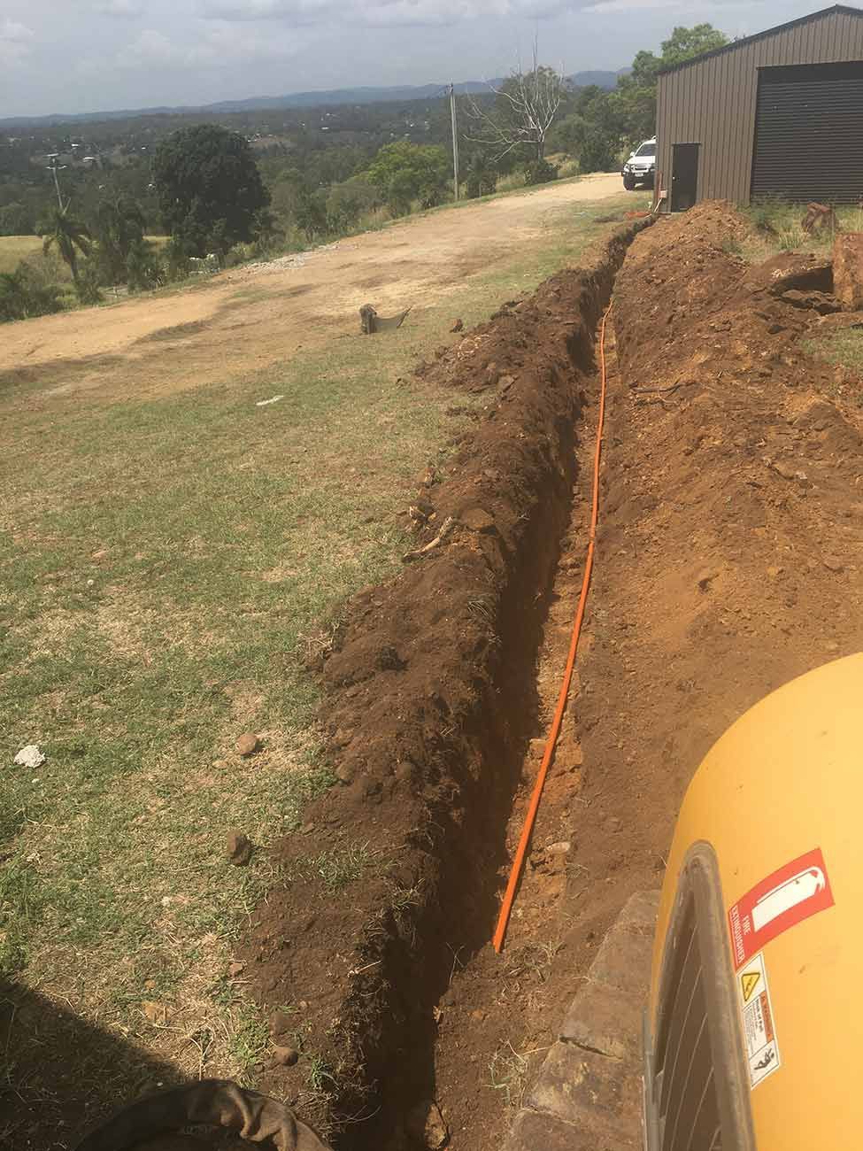 A Yellow Truck Is Driving Down a Dirt Road Next to A Large Pile of Dirt — CK's Milling & Earthworks in Goomeri, QLD