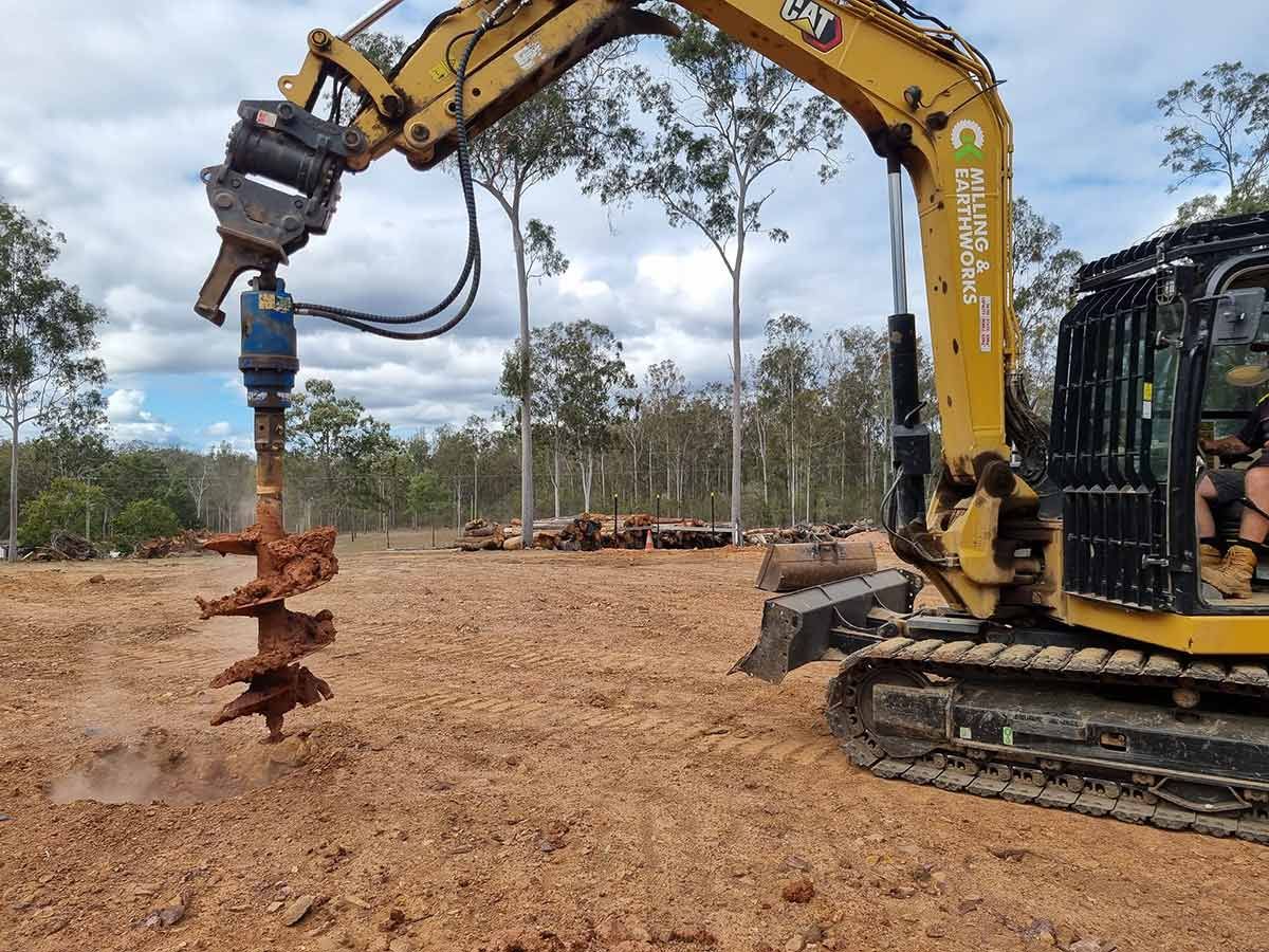 Two Bulldozers Are Working in A Dirt Field with Trees in The Background — CK's Milling & Earthworks in Cooroy, QLD