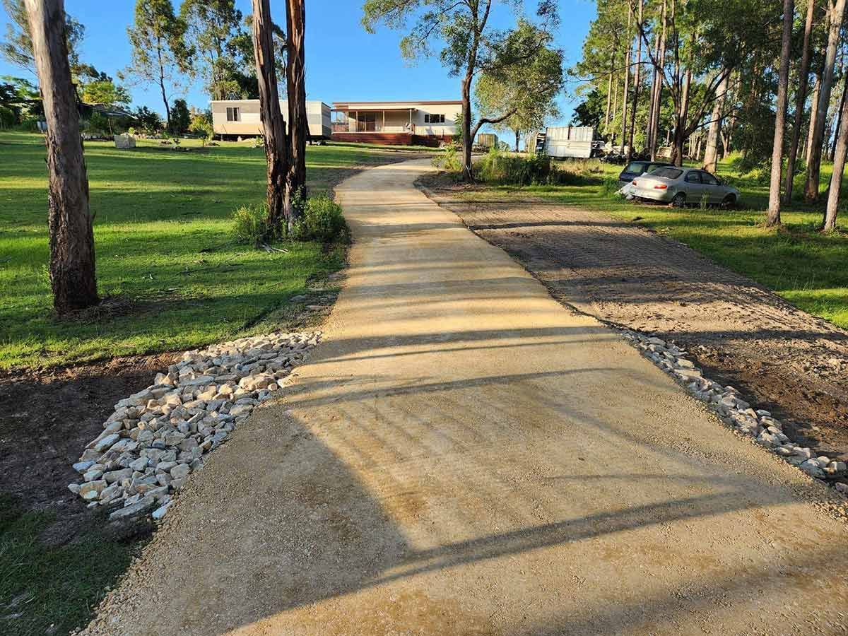 A Concrete Driveway Has Been Laid On Red Dirt — CK's Milling & Earthworks in Kilkvan, QLD