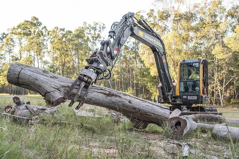 A Large Log Is Being Lifted by An Excavator in A Field — CK's Milling & Earthworks in Bells Bridge, QLD
