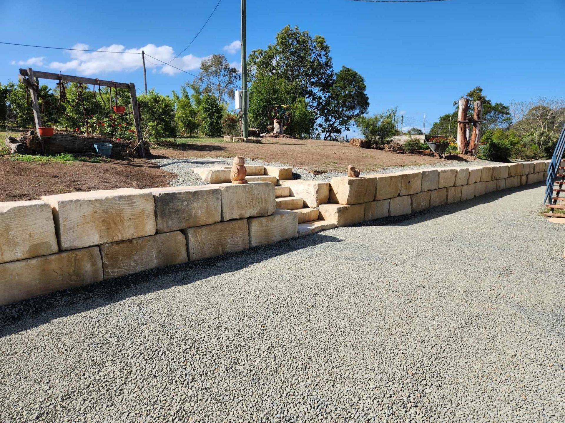 A Wall Of Sandstone Rocks And A Set of Stairs Leads Down To Gravel — CK's Milling & Earthworks in Bells Bridge, QLD