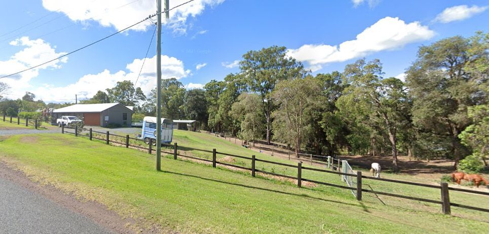 A Wooden Fence Surrounds a Grassy Field Next to A Road — CK's Milling & Earthworks in Veteran, QLD