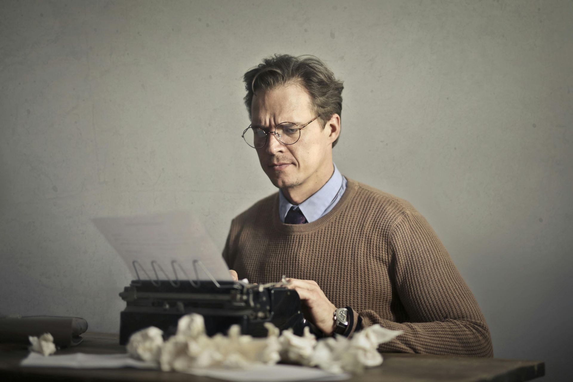 A man is sitting at a table typing on an old typewriter.