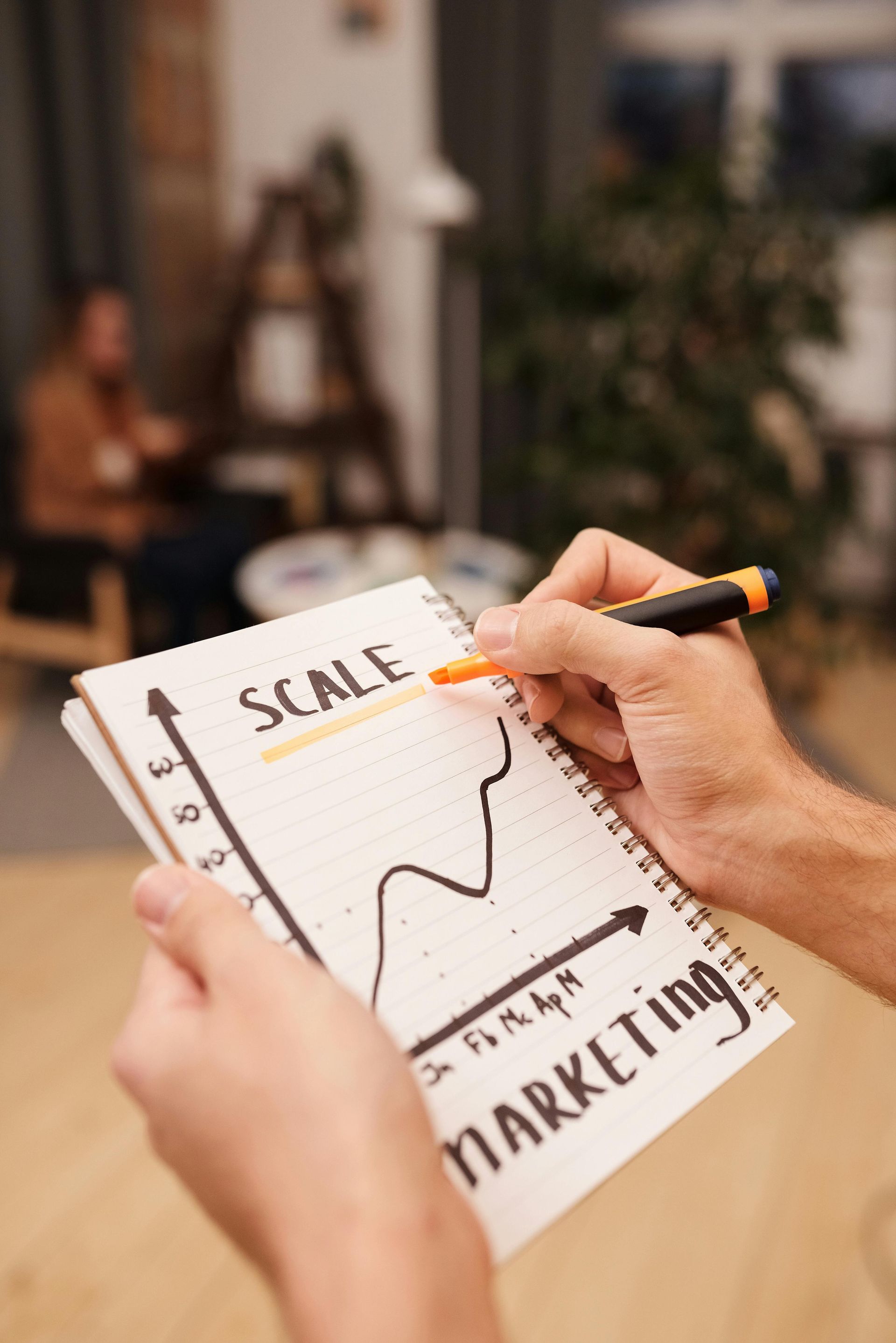 A person is writing on a notebook with a pen.