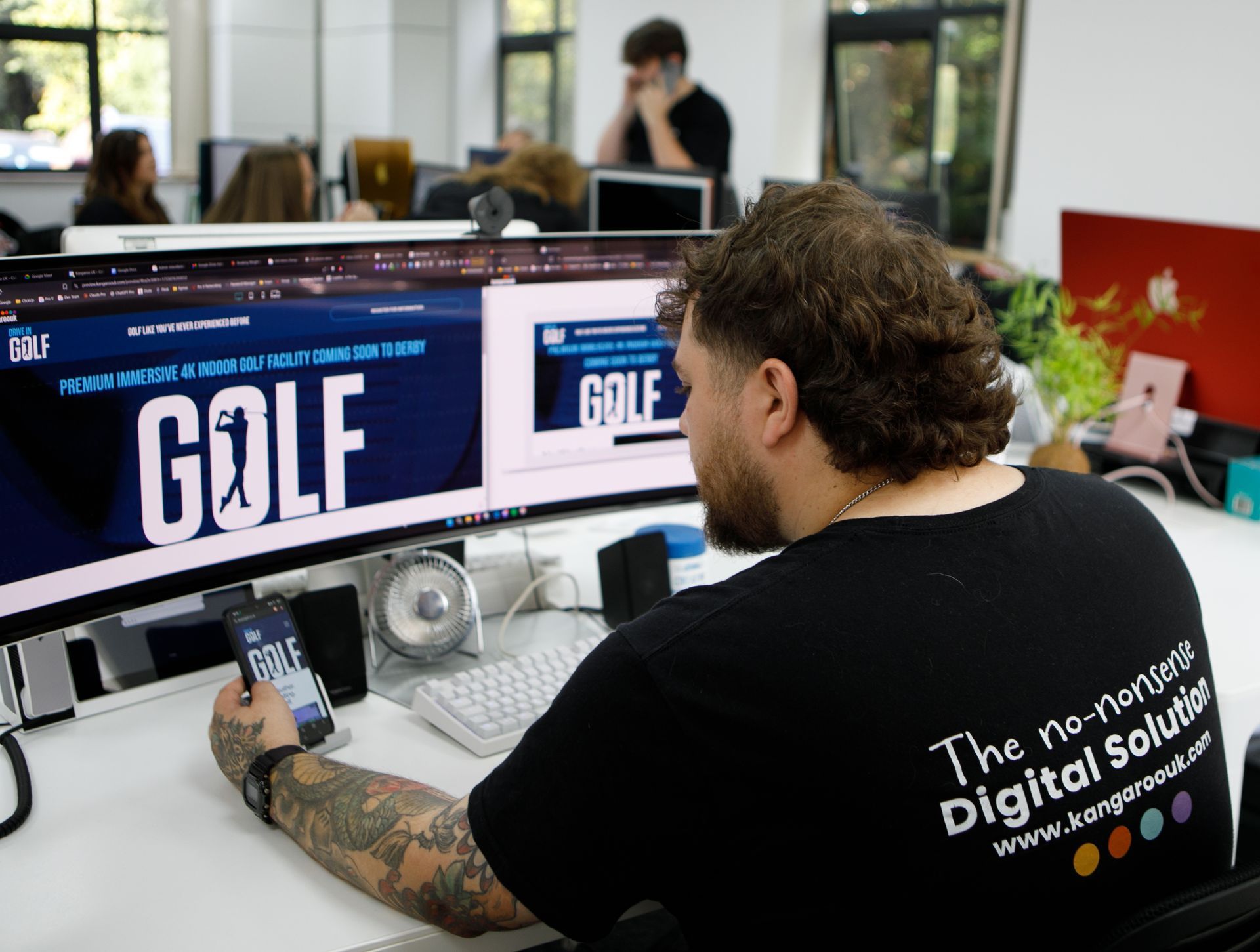 Two people looking at a laptop, pointing at the screen. Office setting, logo in background.