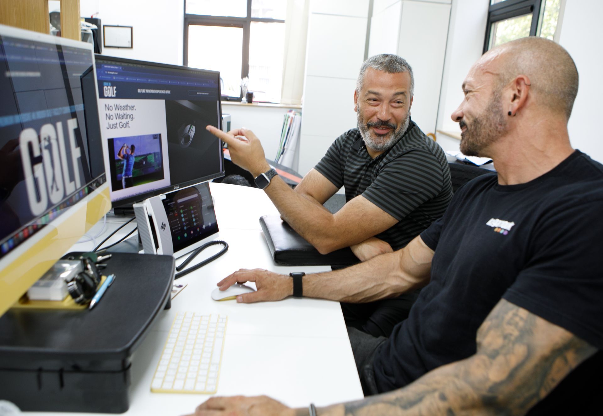 Two men reviewing a computer screen in an office; one points, smiling.