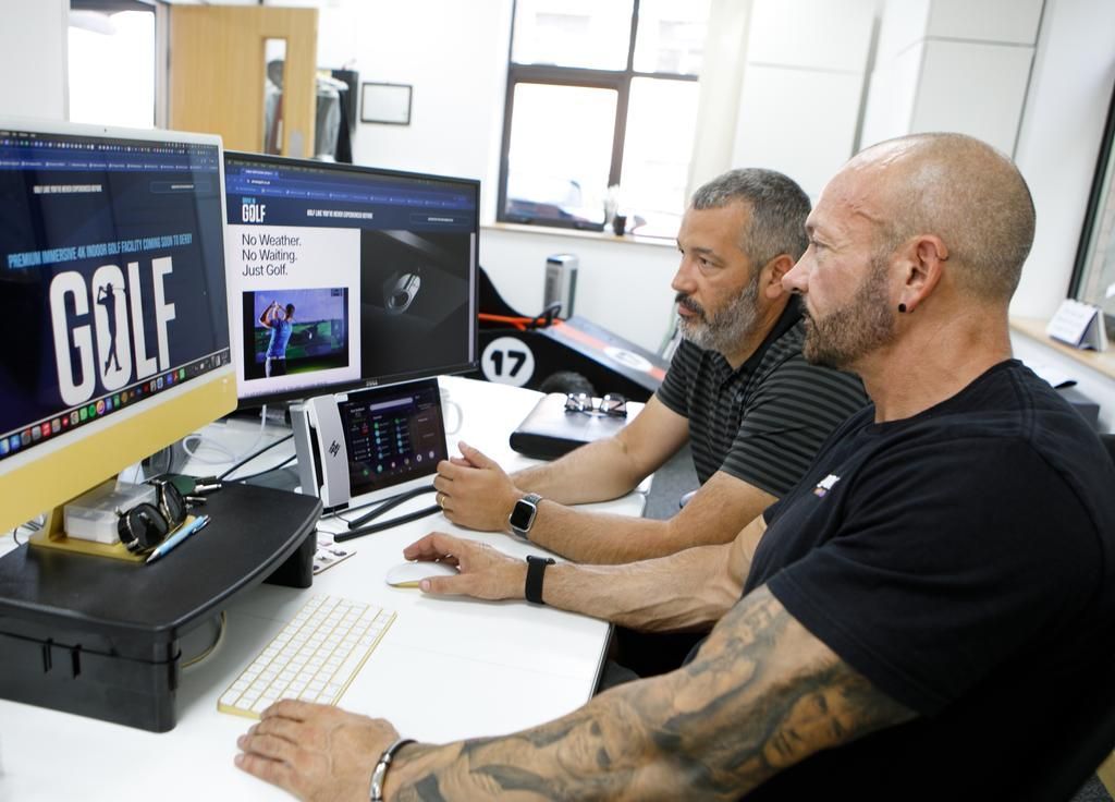 Man at computer in office, looking at two monitors.