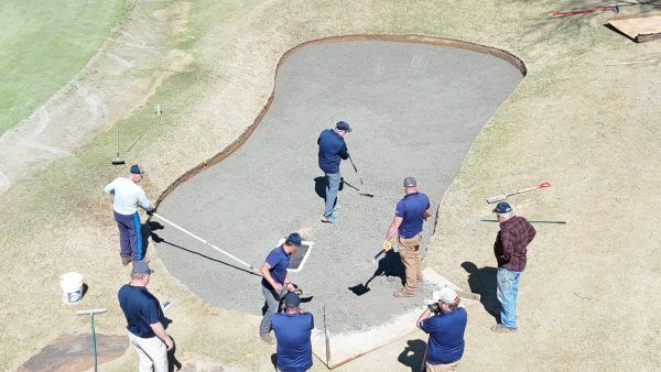 A group of men are working on a golf course.