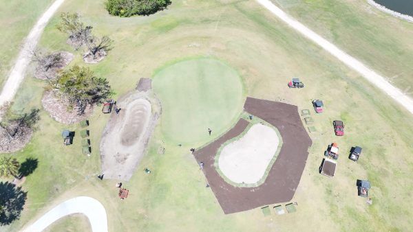 An aerial view of a park with a golf course and a pond.