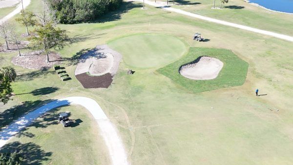 An aerial view of a golf course with a lake in the background.