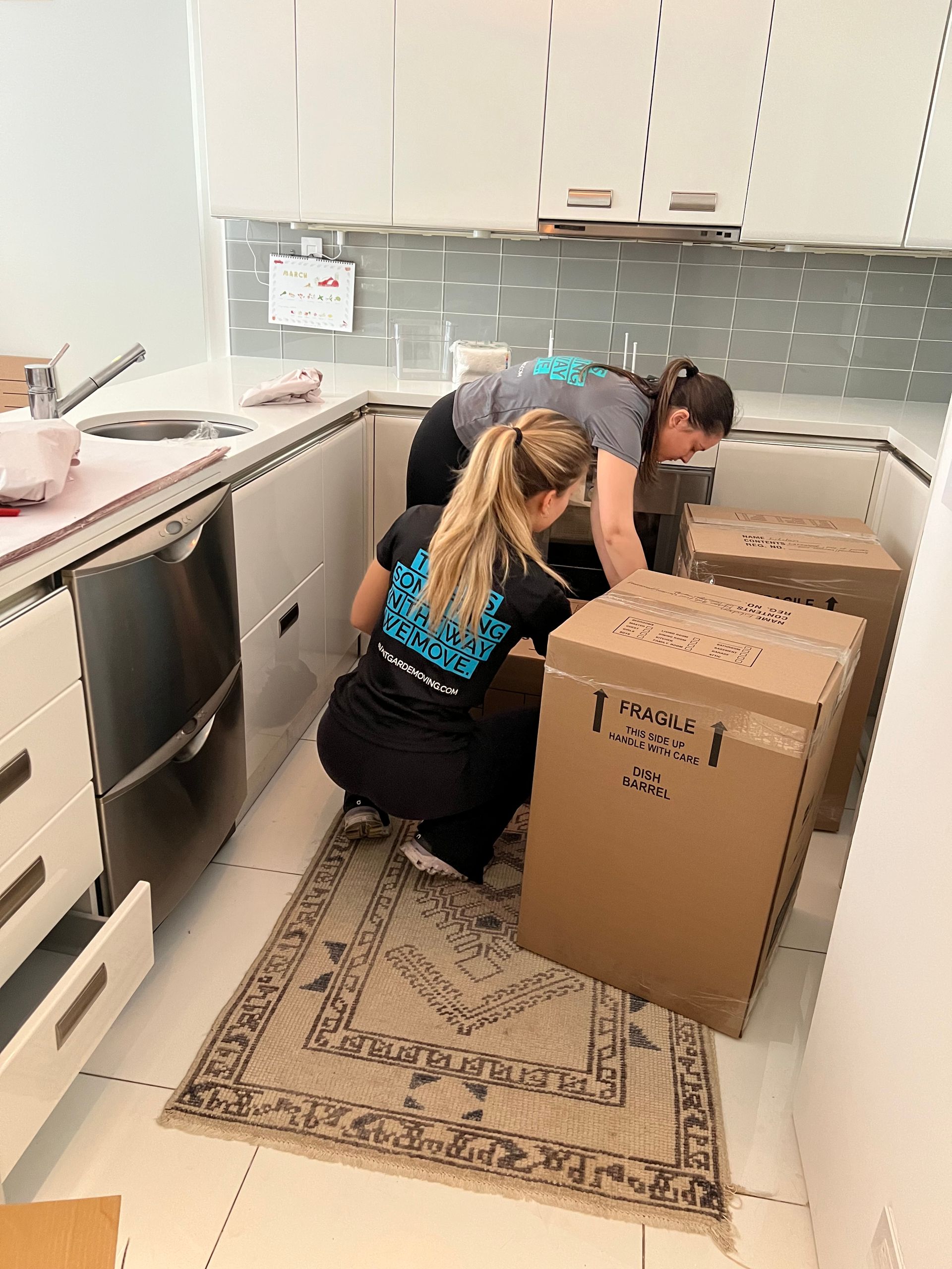 Photo of Avant-Garde's movers and packers, working in the kitchen  -closing up and labeling packed boxes.