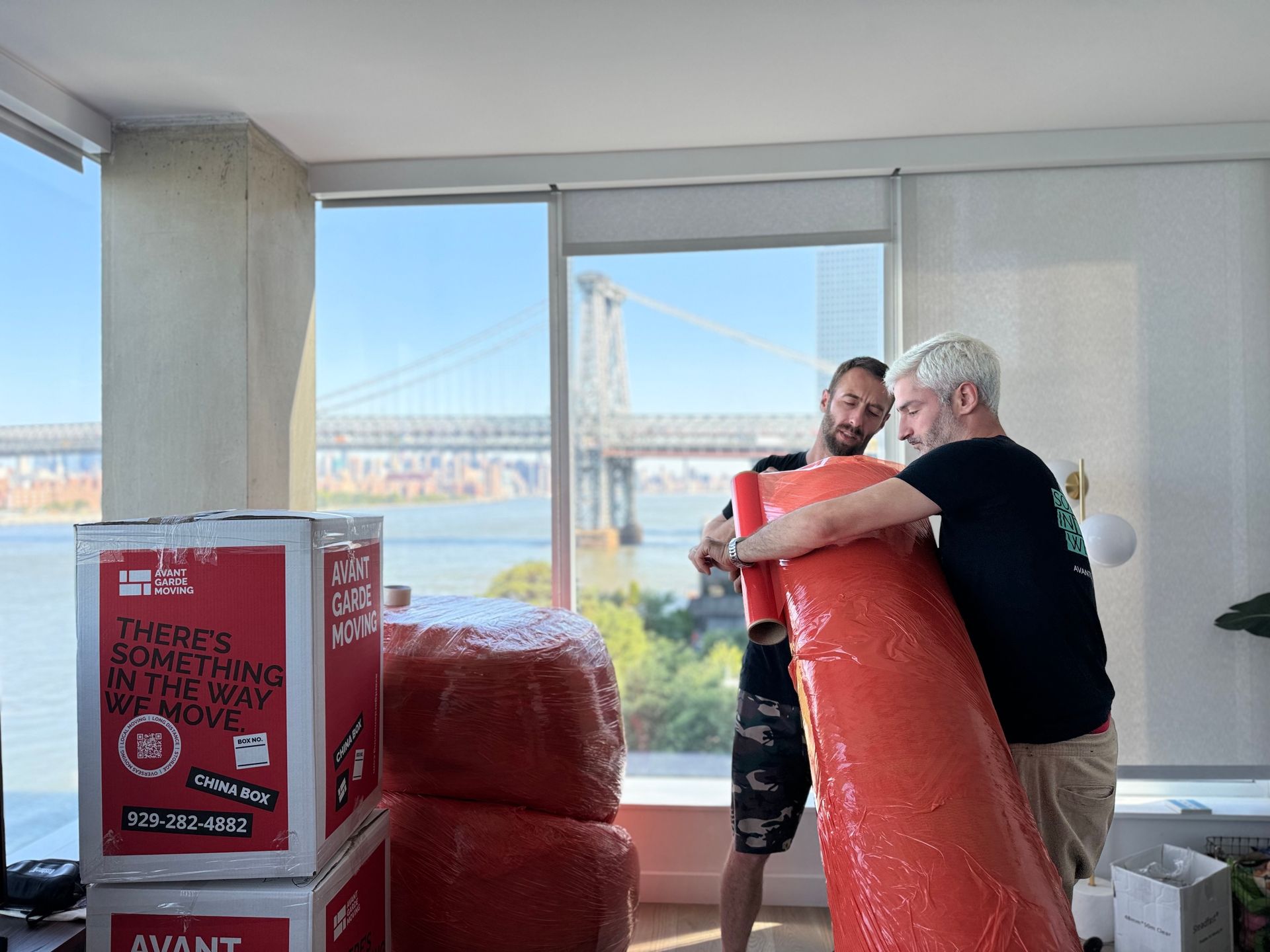Photo of our movers packing/wrapping rug in the Williamsburg, Brookyln apartment overlooking the East River & Williamsburg Bridge 