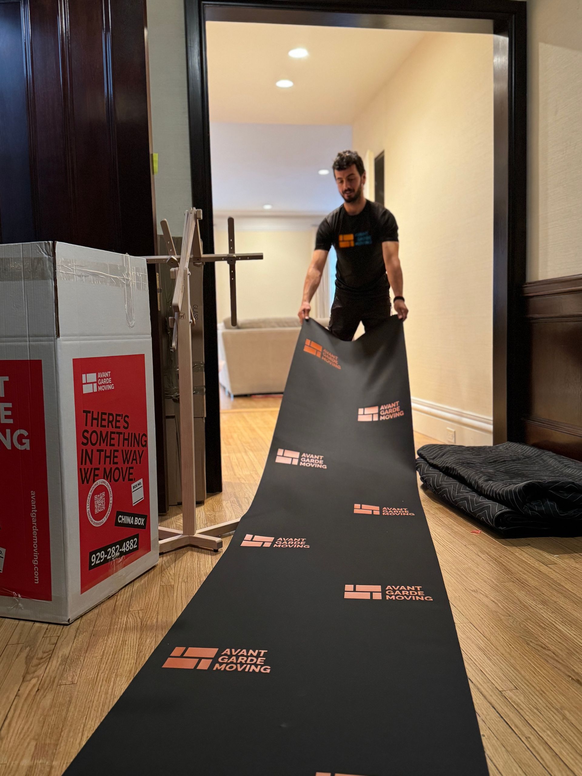 Photo of our long distance movers spreading out our customized floor mat. 