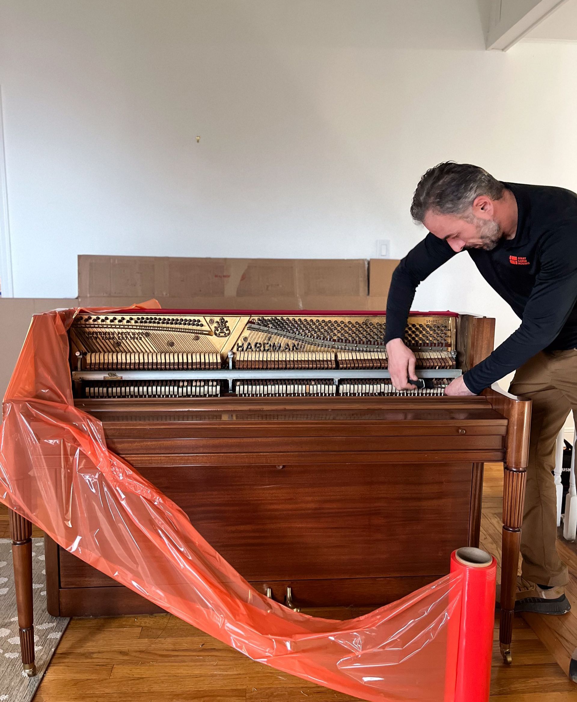 Photo of our expert piano mover wrapping and preparing the upright piano for a move