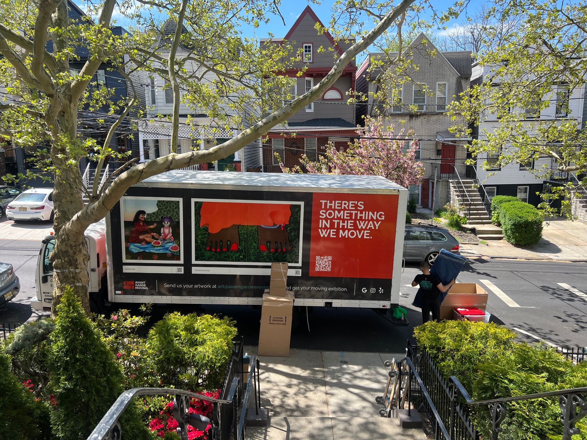 Avant-Garde moving truck parked in front of the house; movers loading furniture