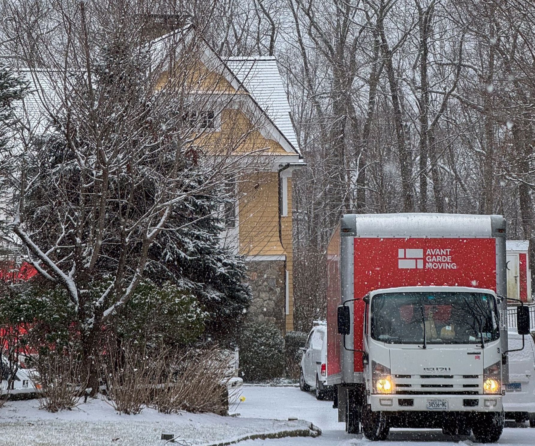 Avant-Garde Moving truck parked in front of a house on a snowy day representing winter moving servic