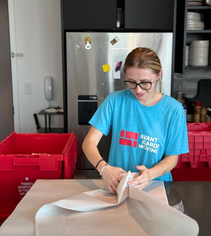 Professional packer packing kitchen dishes with care using protective wrapping – NYC full-service packing by Avant-Garde Moving & Storage
