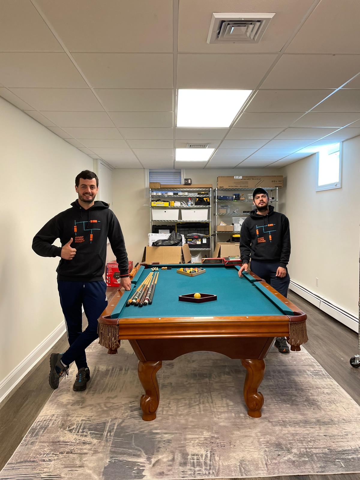 two movers standing next to a pool table