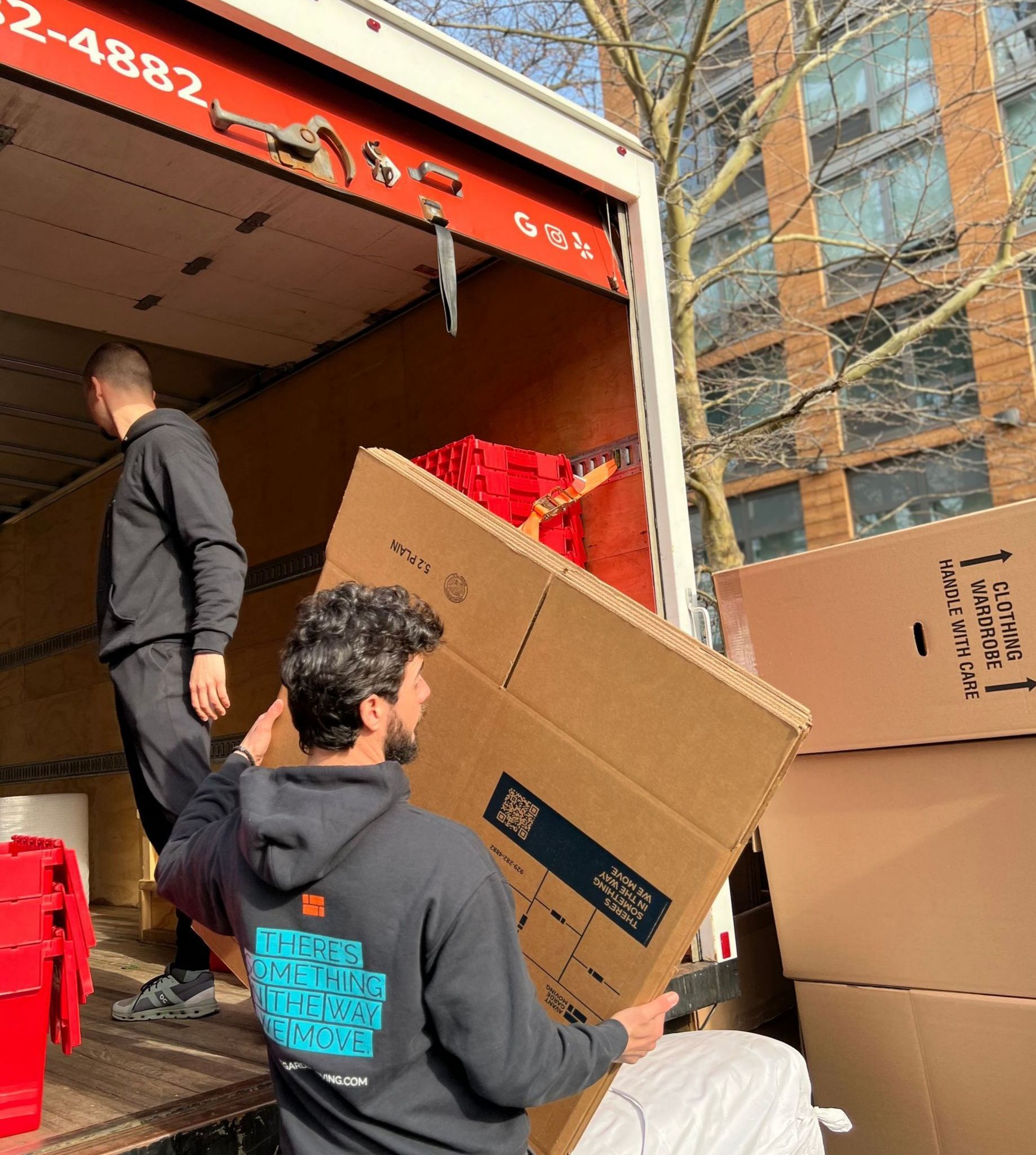 photo of our movers in front of the building in Queens loading the bins and boxes in the truck 