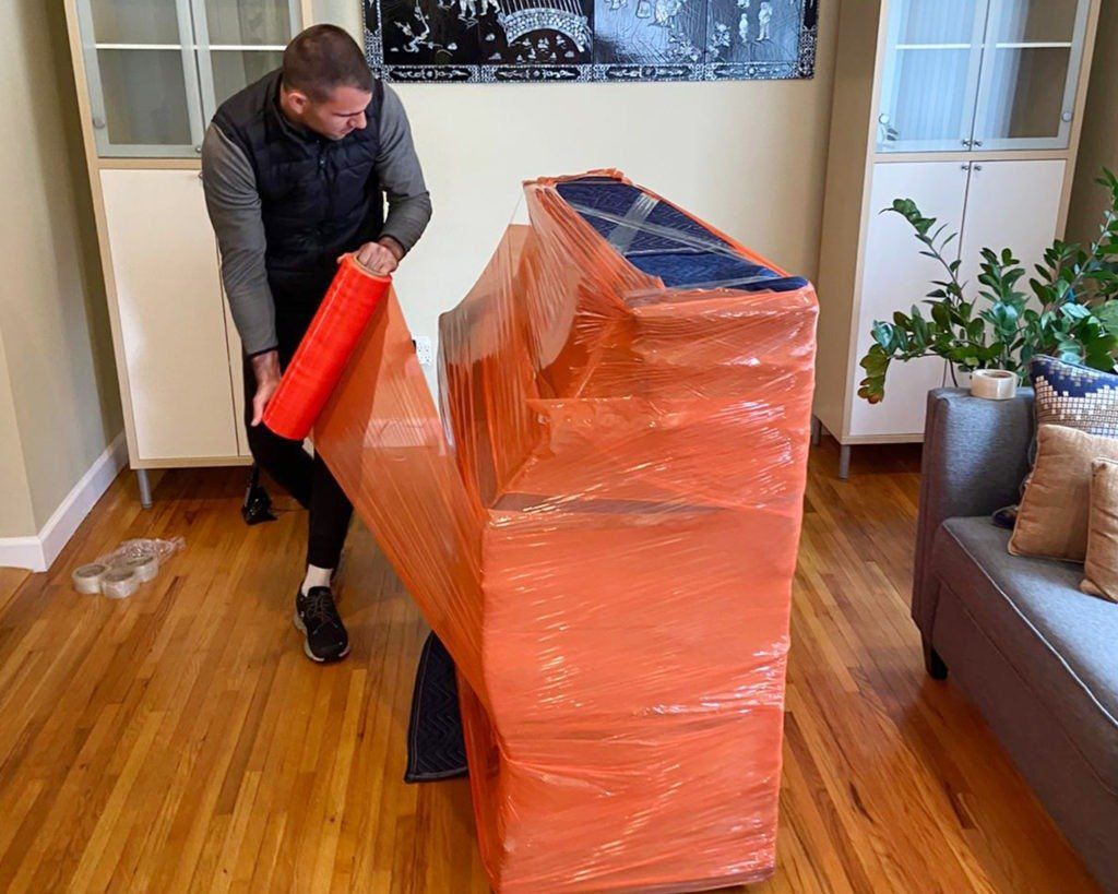 photo of movers wrapping and protecting piano for delivery 