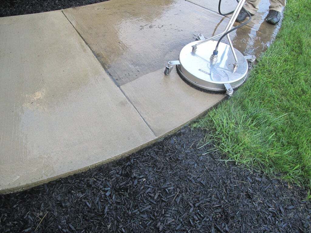 A person is cleaning a sidewalk with a machine.
